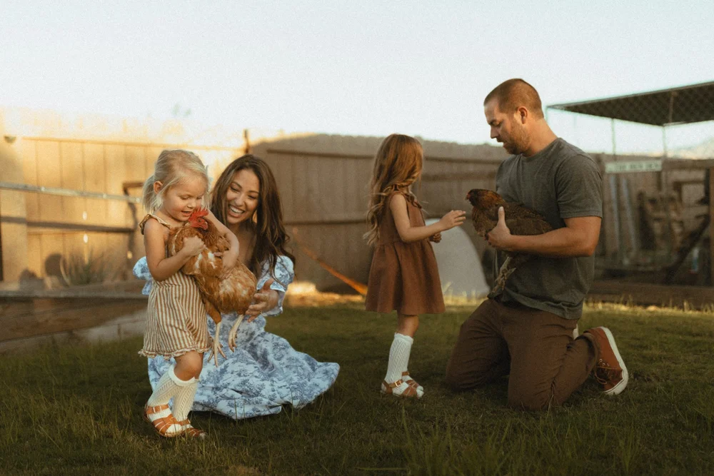 Family of four with two daughters holding chickens