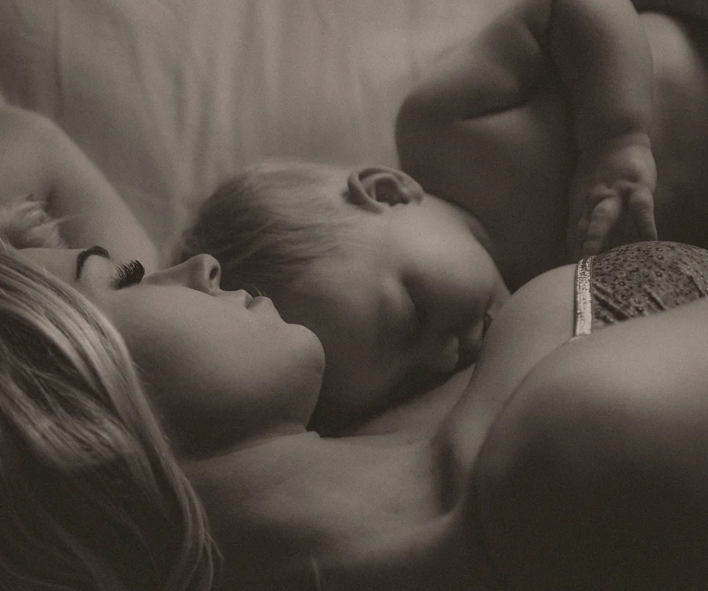 Black and white motherhood image of a toddler nursing